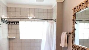 A bathroom with a bathtub, toilet, sink, and a mirror with a decorative frame.