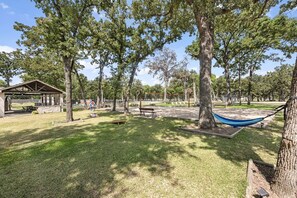 Un parque con mesas de picnic, una hamaca y un pabellón cubierto.