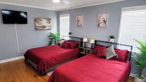 A bedroom with two beds, a ceiling fan, a TV, and artwork on the walls. - Beautiful Escape-Sleeps 12-Patio-Games-Relax (Sumter)