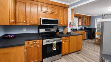 Una cocina moderna con armarios de madera, electrodomésticos de acero inoxidable y encimera negra.