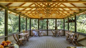 Un espace extérieur abrité, doté d’un plancher en bois, de tables et de chaises.