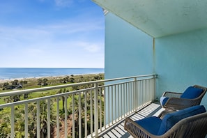 A balcony with wicker chairs, a view of the beach, and a clear sky. - 1372 Shipwatch Oceanfront Beautifully Updated (Fernandina Beach)