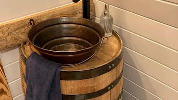 Un évier en forme de baril en bois, doté d’un robinet et d’un récipient en verre.