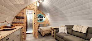 Interior acolhedor de uma cabana com quarto no mezanino, cozinha compacta e área de estar.