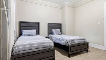 A room with two single beds, each with a wooden headboard and striped bedding.