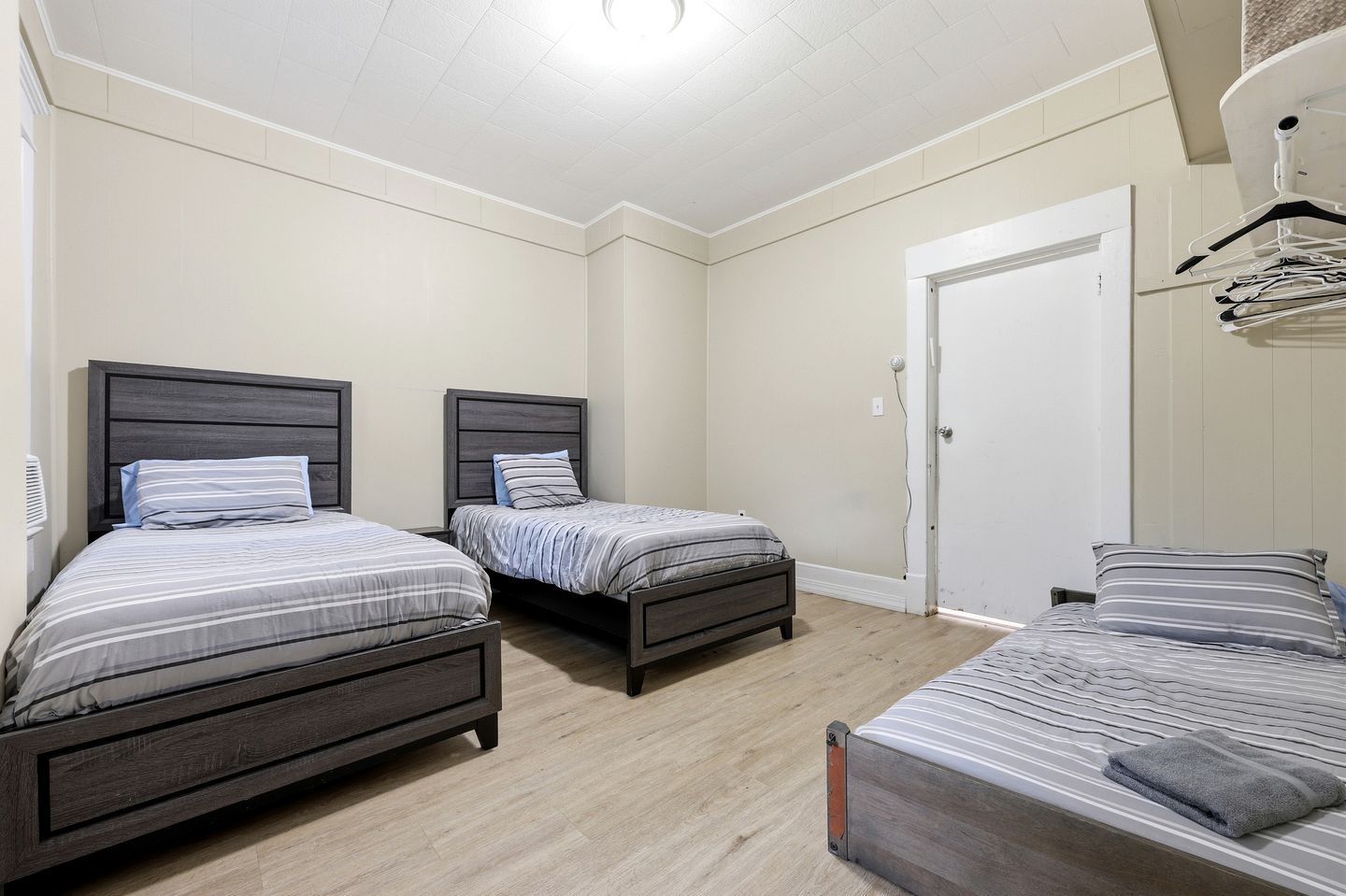 A bedroom with two single beds, a wardrobe, and a door.