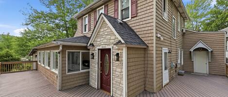 A two-story house with a deck, a garage, and a small attached structure.