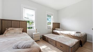 A bedroom with two beds, a nightstand, and a window.
