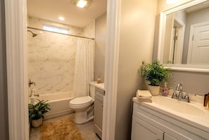 Un bagno con vasca, servizi igienici, lavandino e specchio.