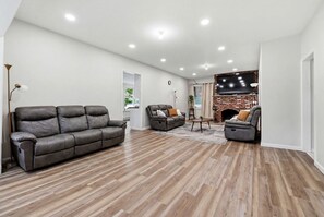 Amplia sala de estar con chimenea, sofás de cuero y televisor de pantalla plana.