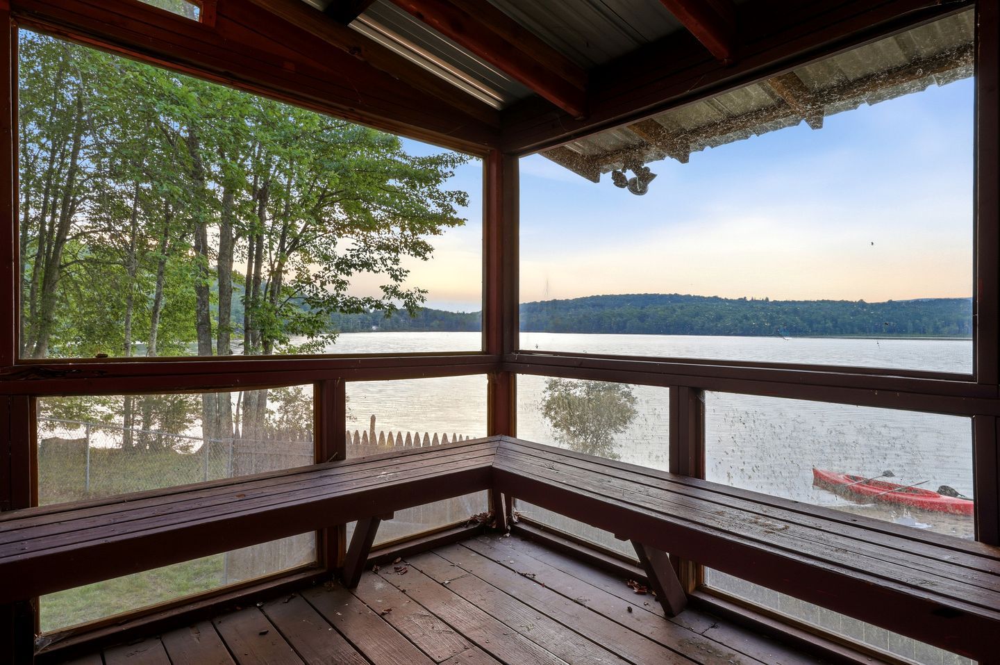 A wooden deck with a bench overlooking a lake, surrounded by trees.