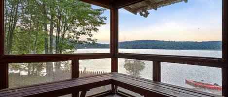 A wooden deck with a bench overlooking a lake, surrounded by trees.