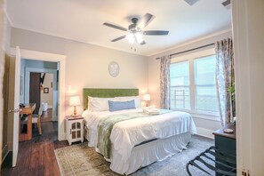 A bedroom with a bed, bedside lamps, a ceiling fan, a window with curtains, and a small table with a lamp. - Centrally Located King Bed Midtown Liberty 2697 (Memphis)