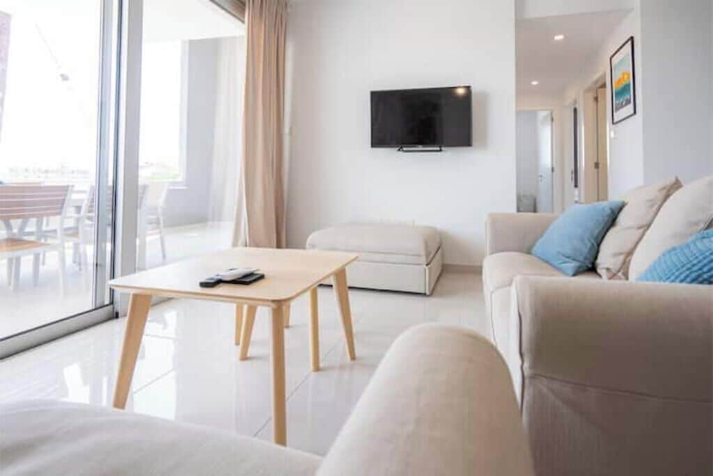 A modern living room with a sofa, a coffee table, and a TV mounted on the wall.