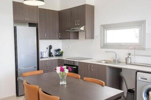 Eine moderne Küche mit dunklen Schränken, einem Edelstahlkühlschrank, einem Einbauofen und einem Fenster über der Spüle.