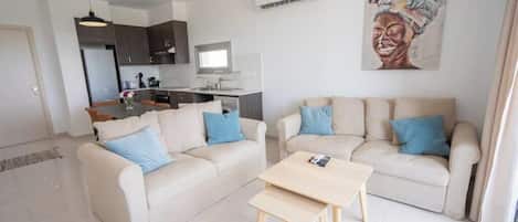 A modern living room with two sofas, a coffee table, and a kitchen in the background.
