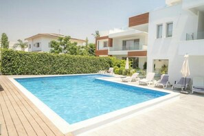 Ein Swimmingpool mit Liegestühlen und einer Holzterrasse.
