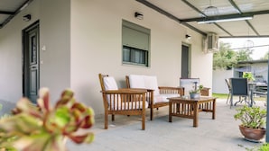 Um pátio com móveis de madeira, uma mesa e plantas em vasos.