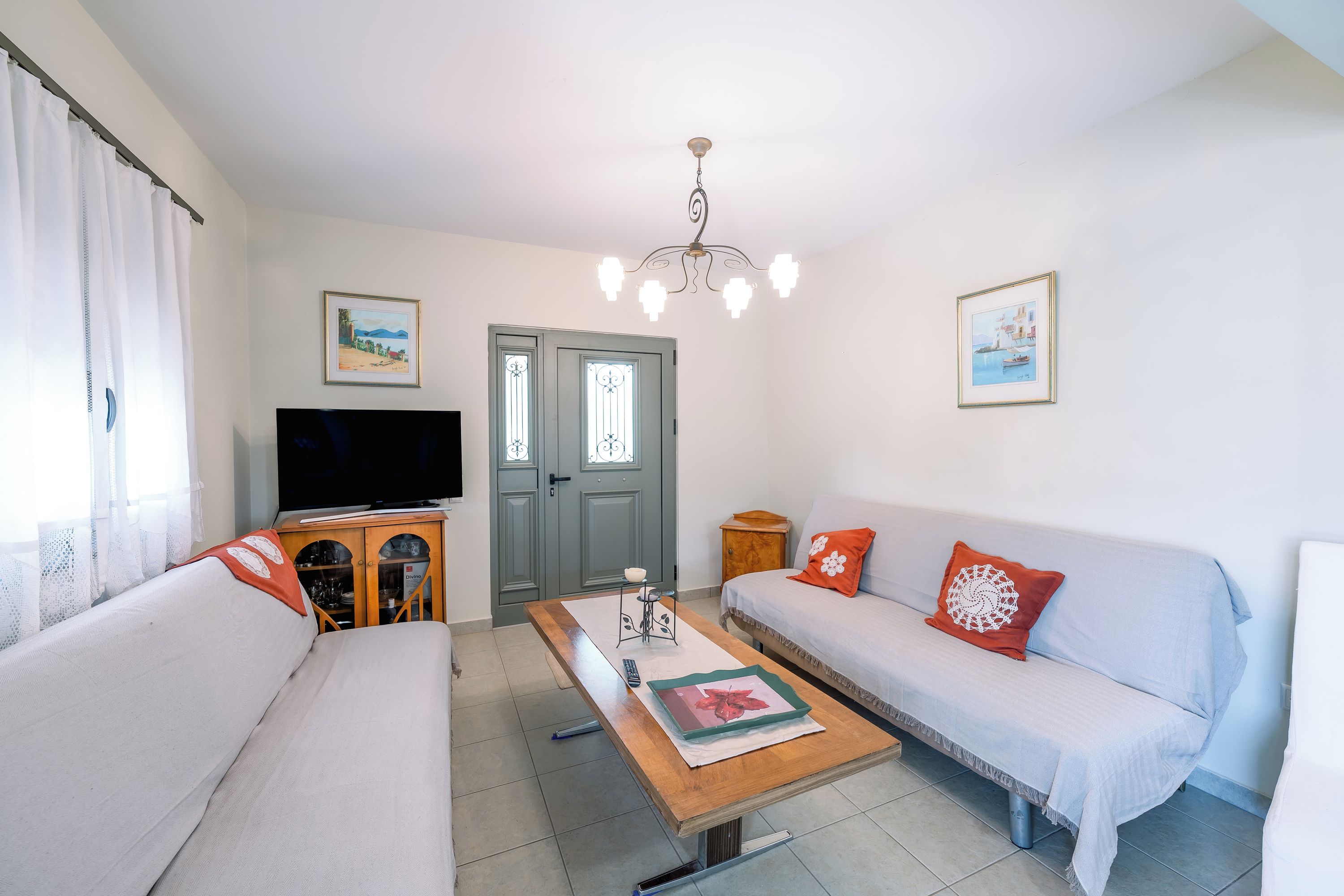 A living room with a sofa, a coffee table, a television, and a door.
