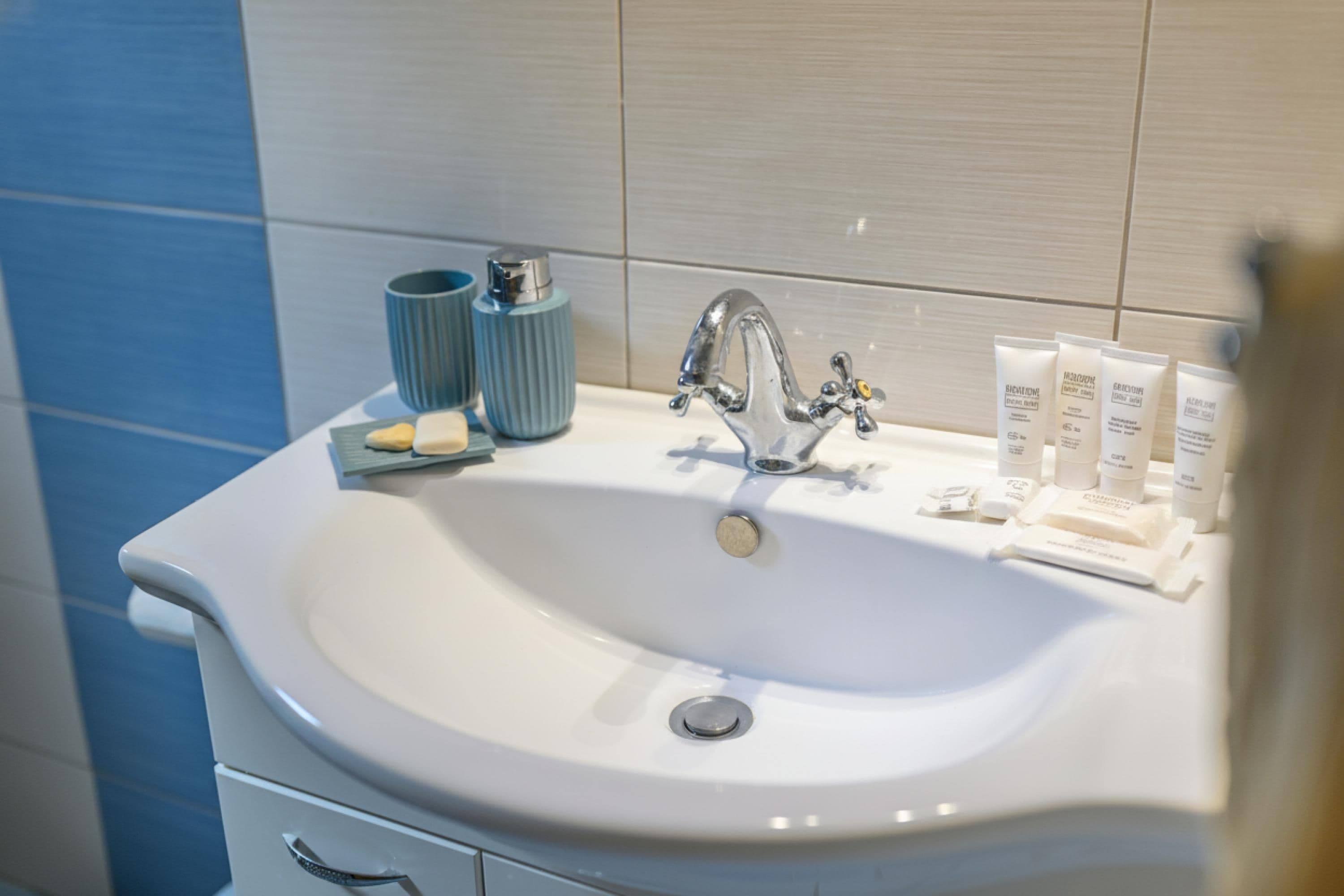 A bathroom with a white sink, a silver faucet, and toiletries on the counter.
