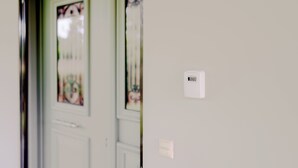 Eine Tür mit einem satinierten Glasfenster und einem kleinen weißen Gerät an der Wand.