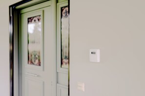 A door with a frosted glass panel and a small white device on the wall. - Antonia's Olive Yard House (Pyrgos)