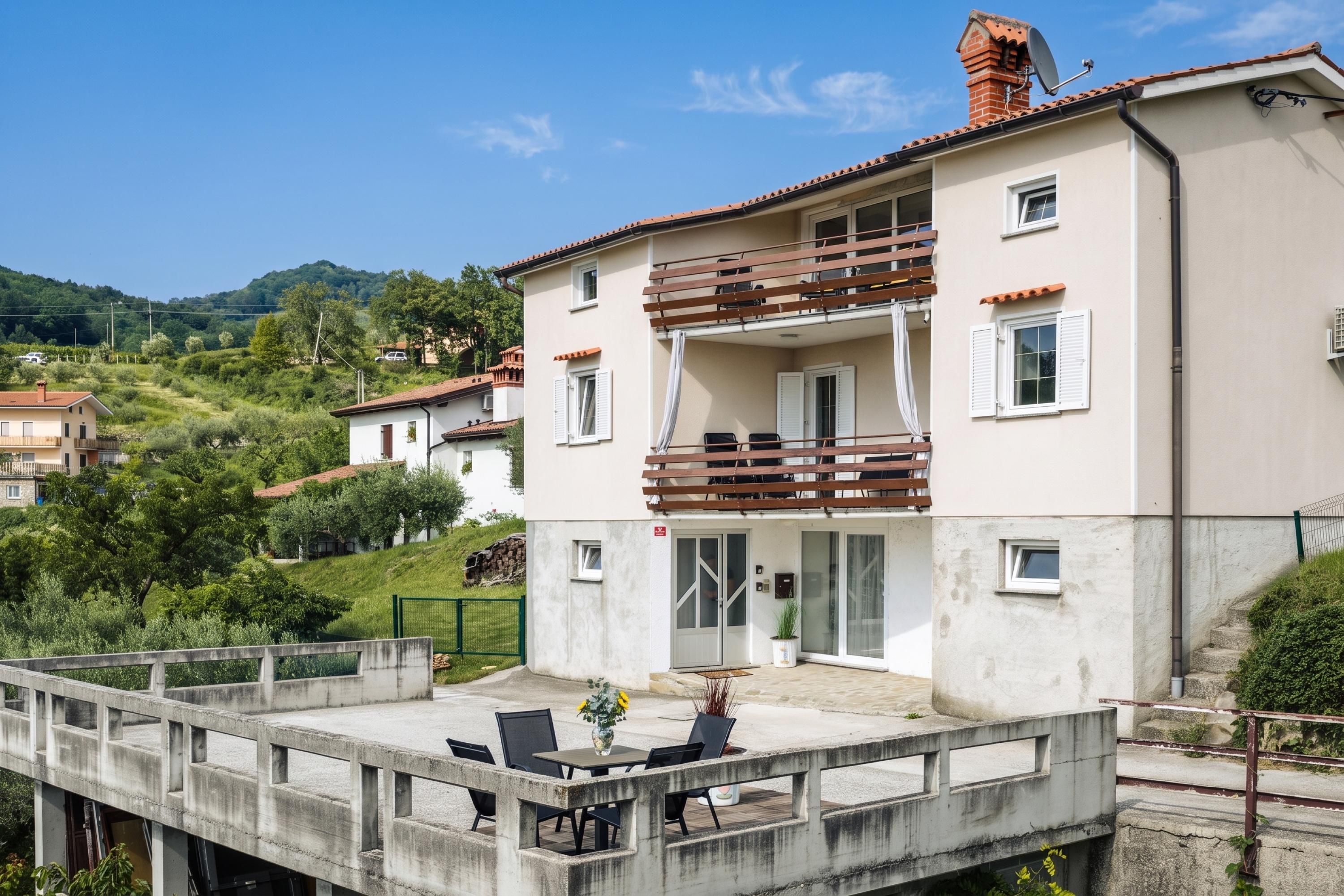 Ein zweistöckiges Gebäude mit Balkon, Sitzgelegenheit im Freien und Blick auf die umliegende Landschaft.
