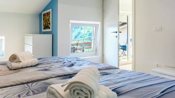Camera d'albergo con un letto, una finestra, una porta che dà su uno spazio esterno e un'opera d'arte appesa al muro.