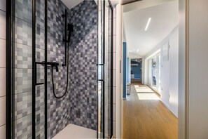 Un bagno moderno con box doccia in vetro e parete rivestita in piastrelle.