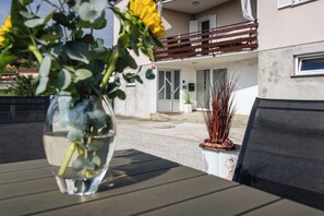 Een tafel met een bloevas, een plant in pot en een stoel.