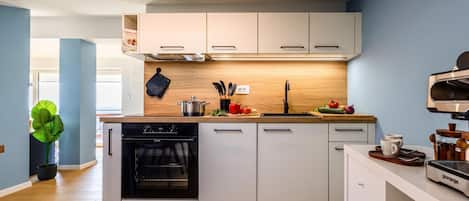 A modern kitchen with white cabinets, a built-in oven, and a coffee machine.