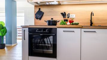 Una cucina moderna con forno integrato, un piano di lavoro in legno e diversi utensili da cucina.