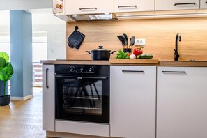 Een moderne keuken met een inbouwoven, een houten aanrecht en diverse keukengerei.