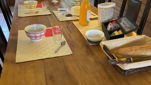 Une cuisine avec une table en bois, divers appareils de cuisine et une fenêtre donnant sur un paysage verdoyant.