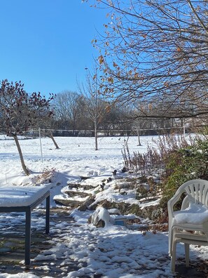 A snowy outdoor area with a bench, a chair, and a small structure.