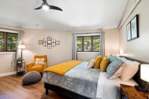 A bedroom with a bed, a chair, a lamp, and a wall with framed artwork. - Design Cabin with Jacuzzi and Porch in Sister Bay, Wisconsin (Sister Bay)