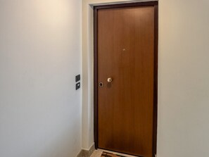 Eine geschlossene Holztür mit Knauf und einem kleinen rechteckigen Gegenstand an der Wand links davon.