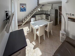 Eine moderne Küche mit Essbereich, einer Treppe und Blick zum Wohnbereich.