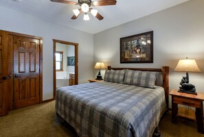 A bedroom with a bed, two bedside tables with lamps, a ceiling fan, a door, and a framed picture on the wall. - Wonderful Cabin with Game Room and Swimming Pool in Branson, Missouri (Branson)