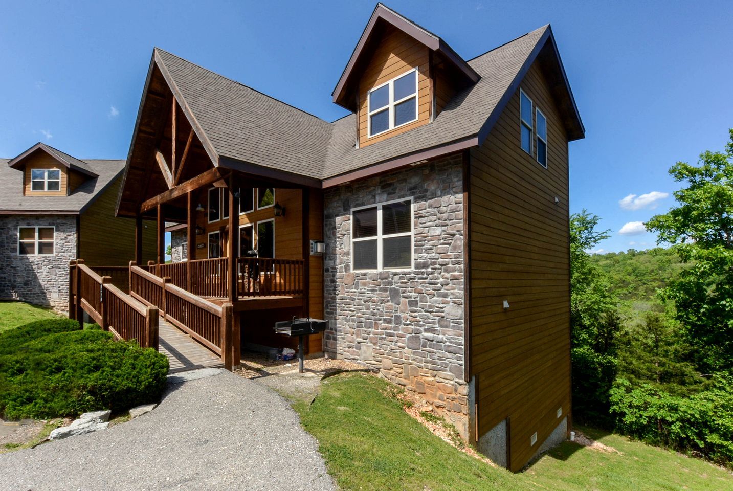A lodge with a stone facade, wooden deck, and a covered porch.
