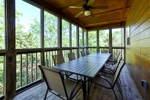 A covered outdoor area with a table and chairs, large windows, and a ceiling fan. - Wonderful Cabin with Game Room and Swimming Pool in Branson, Missouri (Branson)