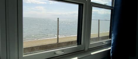 A window with a view of a beach and the sea.