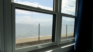 Een uitzicht op een strand en de zee vanuit een raam.
