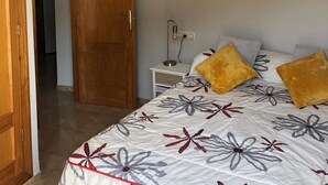 Un dormitorio con una cama, una mesita de noche, un cuadro abstracto en la pared y una puerta de madera.