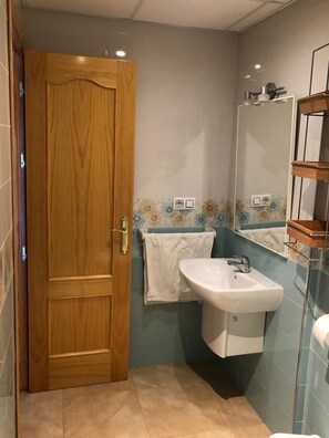Ein Badezimmer mit Holztür, Waschbecken, Spiegel und Handtuchhalter.