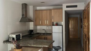 Una cocina moderna con encimeras de granito, armarios de madera, un microondas integrado y una campana extractora de acero inoxidable.