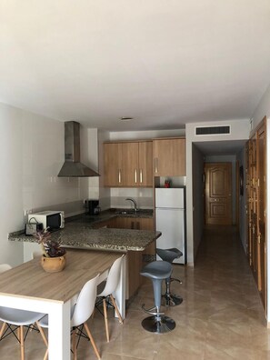 Eine moderne Küche mit Granit-Arbeitsplatten, Holzschränken, einer eingebauten Mikrowelle und einer Edelstahl-Dunstabzugshaube.