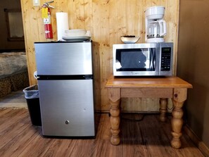 A kitchen with a stainless steel refrigerator, a microwave on a wooden table, and a coffee maker on the wall. - Charming Pet Friendly Studio Cabin near Metcalfe Bay, Big Bear, California (Big Bear Lake)