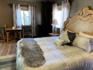 A bedroom with a large bed, a wooden headboard, a desk, and a chair. - Charming Pet Friendly Studio Cabin near Metcalfe Bay, Big Bear, California (Big Bear Lake)