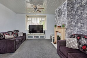 Ein Wohnzimmer mit Fernseher, Sofas, Kamin und Deckenventilator.